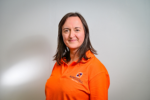 Sarah Wood, Operational Excellence Manager at Kirkstall Precision | A woman with brown hair in an orange polo shirt looks confidently to camera
